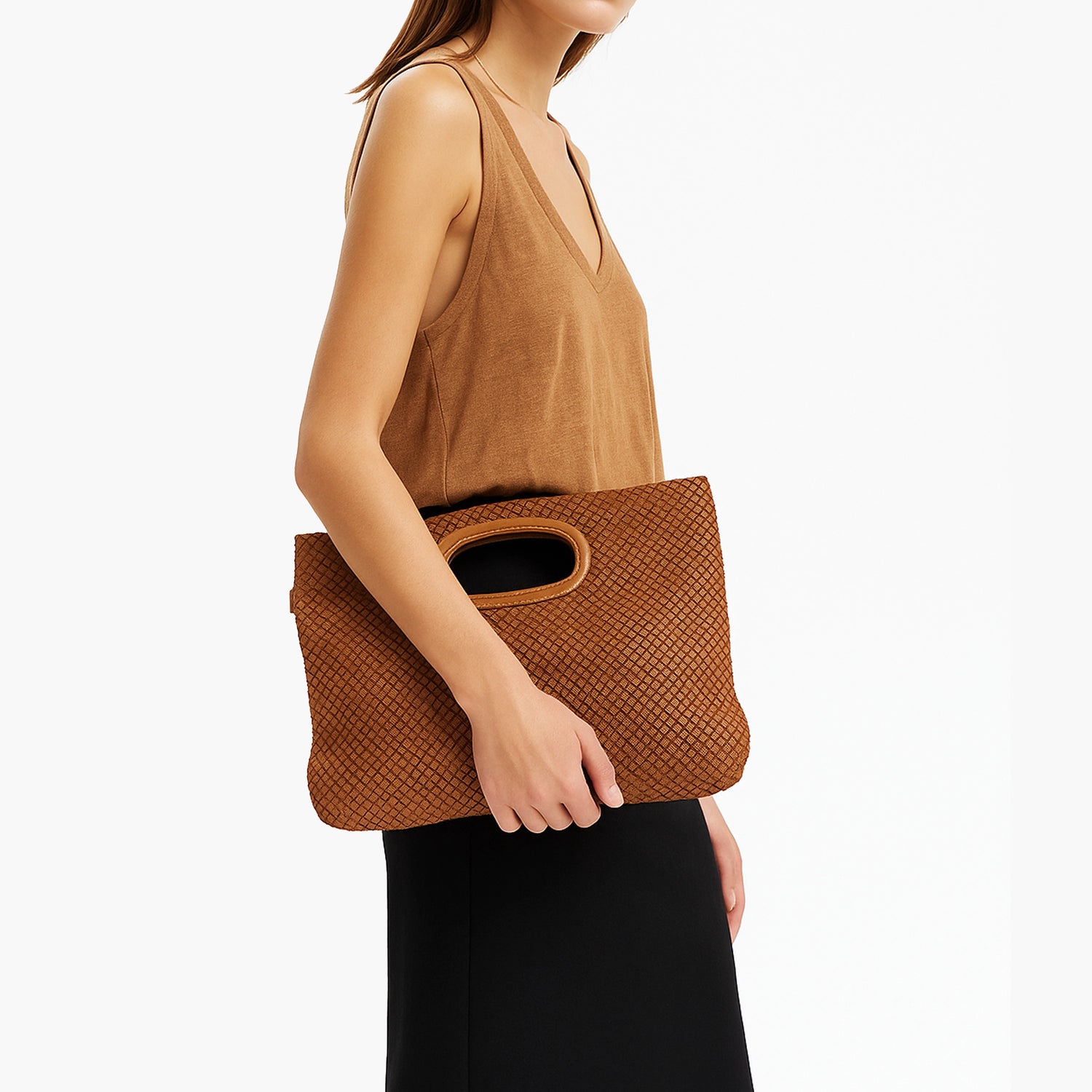 Modella fotografata lateralmente in studio con in mano la borsa Lovelace in pelle intrecciata color cuoio della collezione C-Natural Weave.