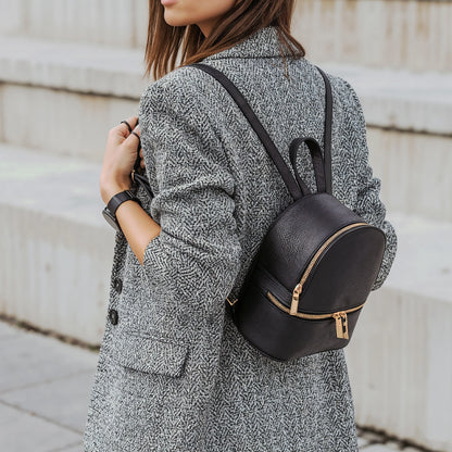 Woman wearing a grey textured coat carrying a black David Halfon leather backpack with gold zippers